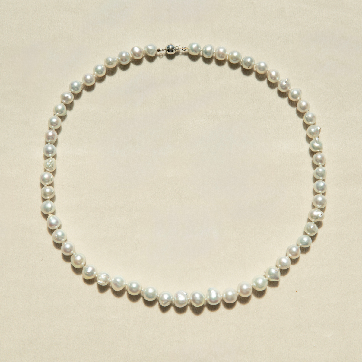 Pearl strand necklace on a beige background