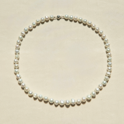 Pearl strand necklace on a beige background