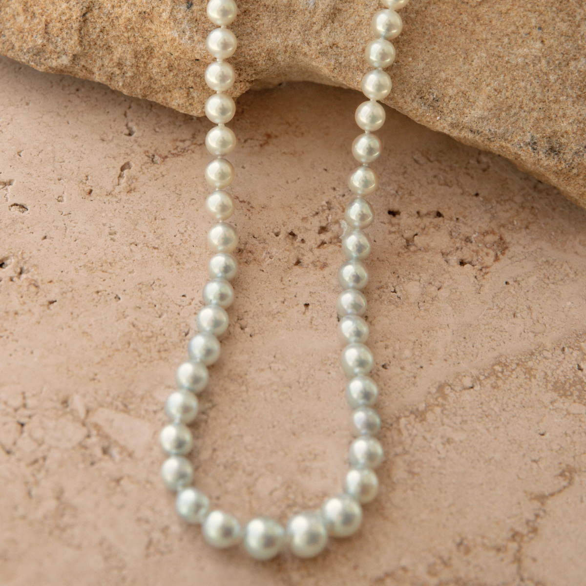 Pearl necklace on a textured stone surface