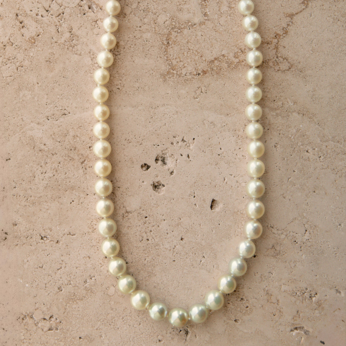 Pearl necklace on a textured beige surface