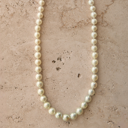 Pearl necklace on a textured beige surface