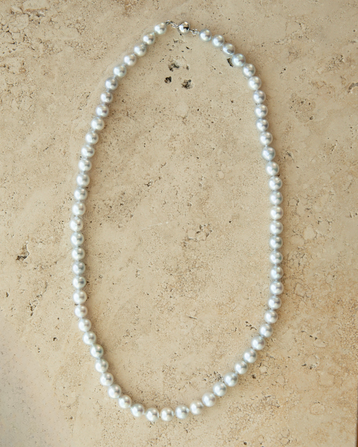 Akoya Pearl Strand Necklace on a beige stone surface