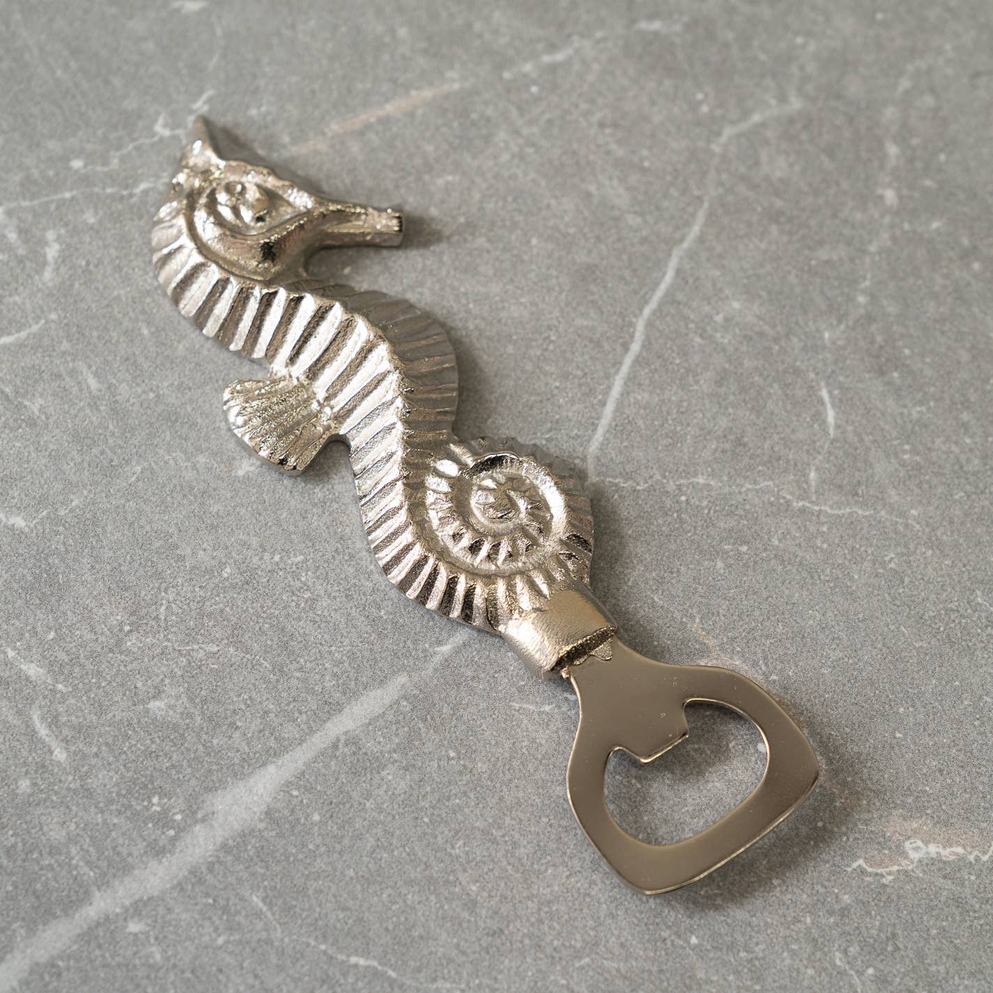 Made from durable stainless steel, this sleek silver bottle opener is not only functional but also adds a touch of coastal charm to your decor. The intricate etched seahorse design showcases attention to detail and craftsmanship.

