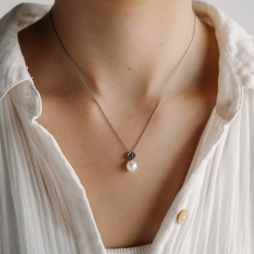 A woman wears her stunning Australian Akoya pearl pendant on a gold chain. This pendant is part of our Seagrass Collection, and features the seagrass motif set on top of our naturally lustrous Akoya pearls.