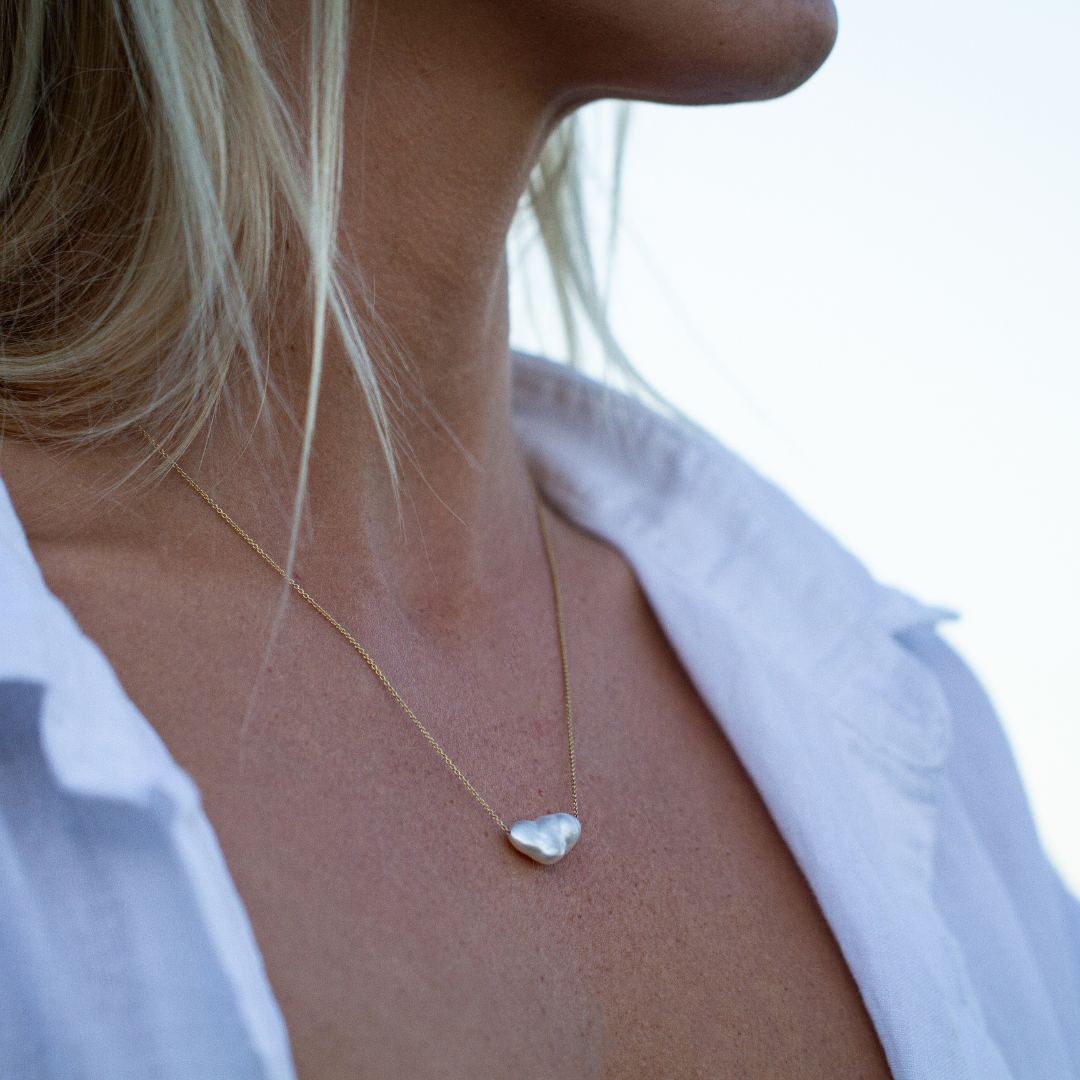 A woman wears her stunning Australian South Sea keshi pearl set on a delicate gold chain necklace.