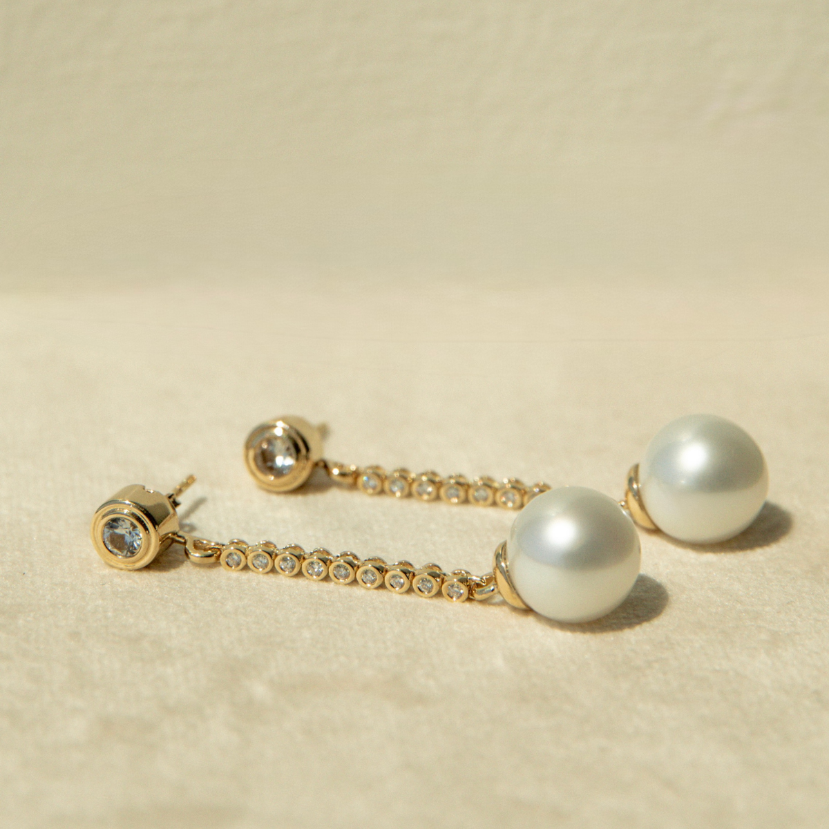 Pearl and gold earring on a beige background