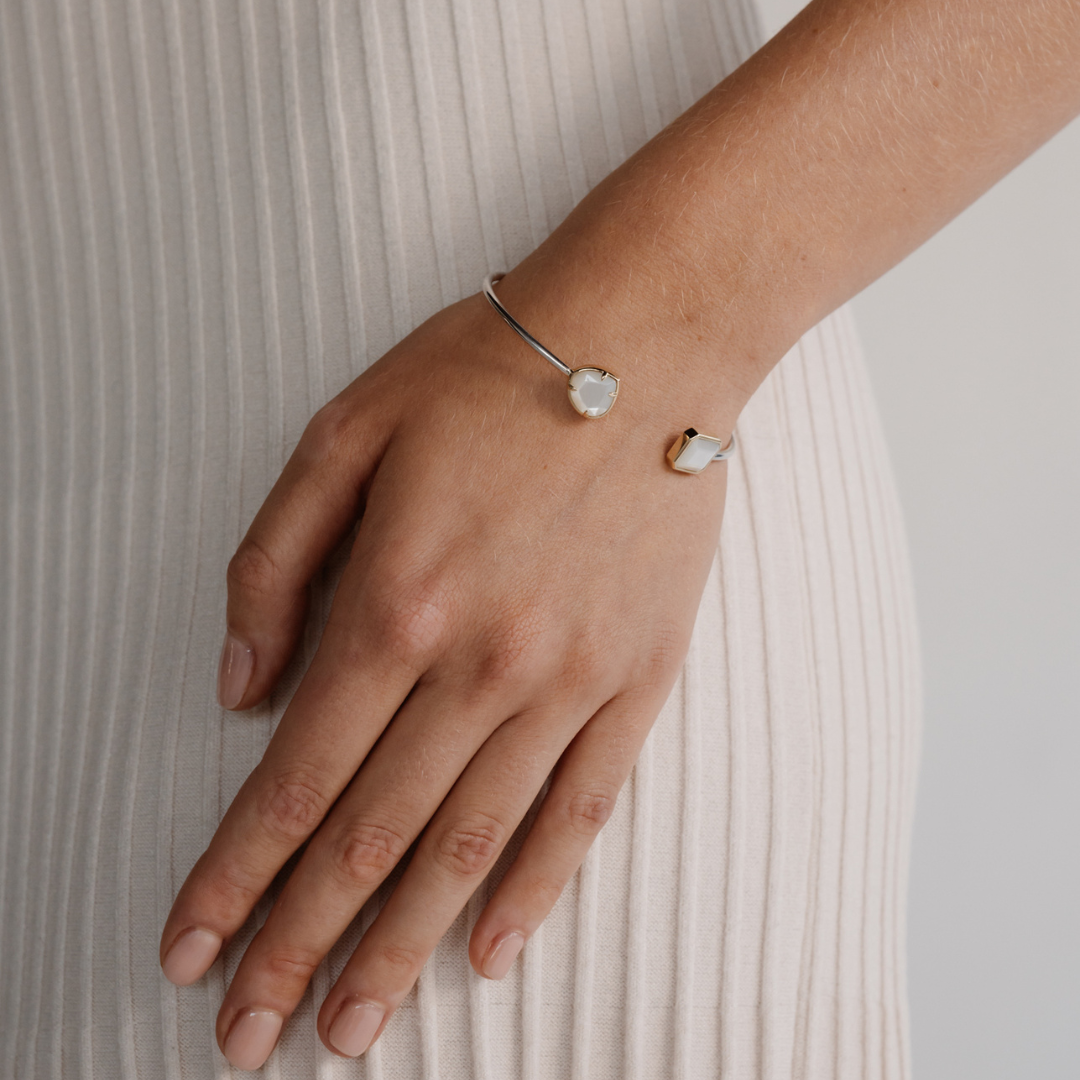 A photo of a woman wearing her stunning Mother of Pearl gemcut bangle set in sterling silver and gold.