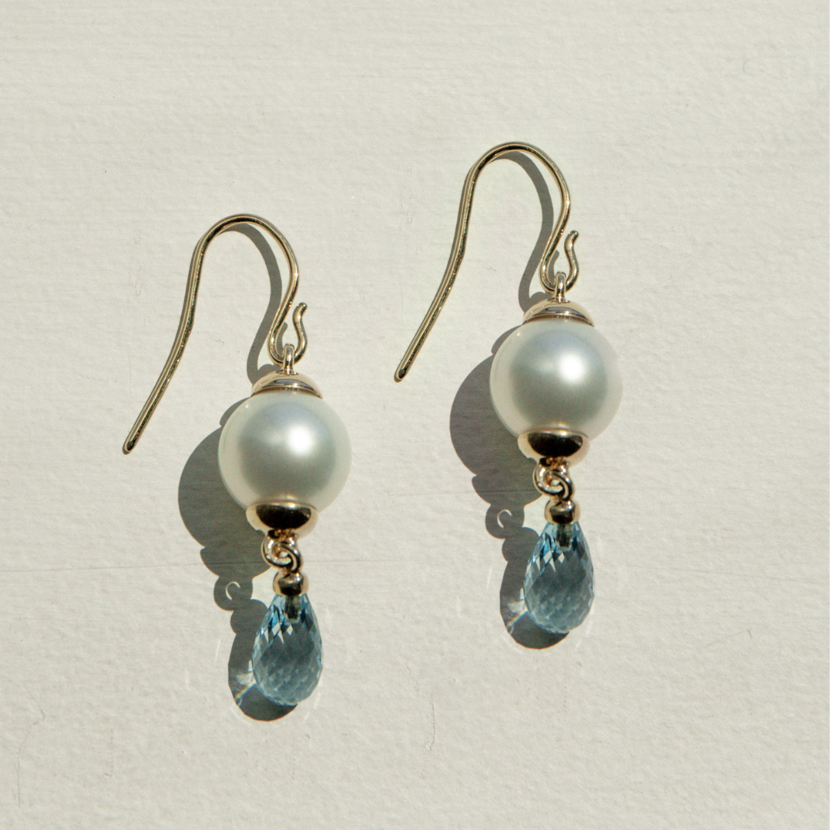 Pair of earrings with pearls and blue gemstones on a light background