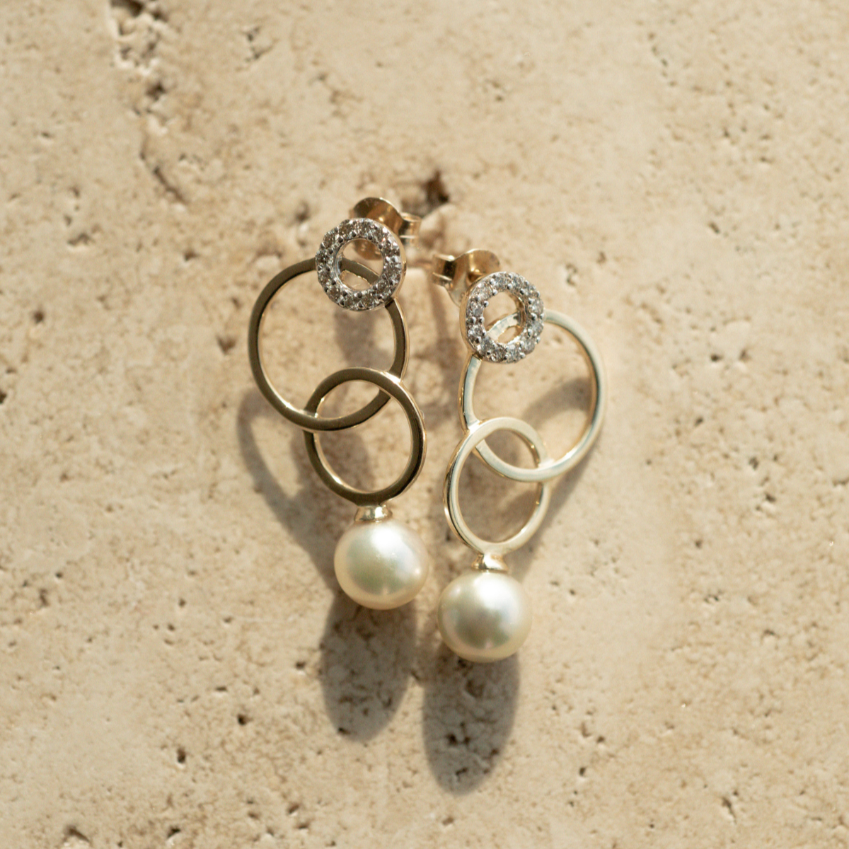 A pair of stunning pearl earrings featuring rings of gold in varying sizes.