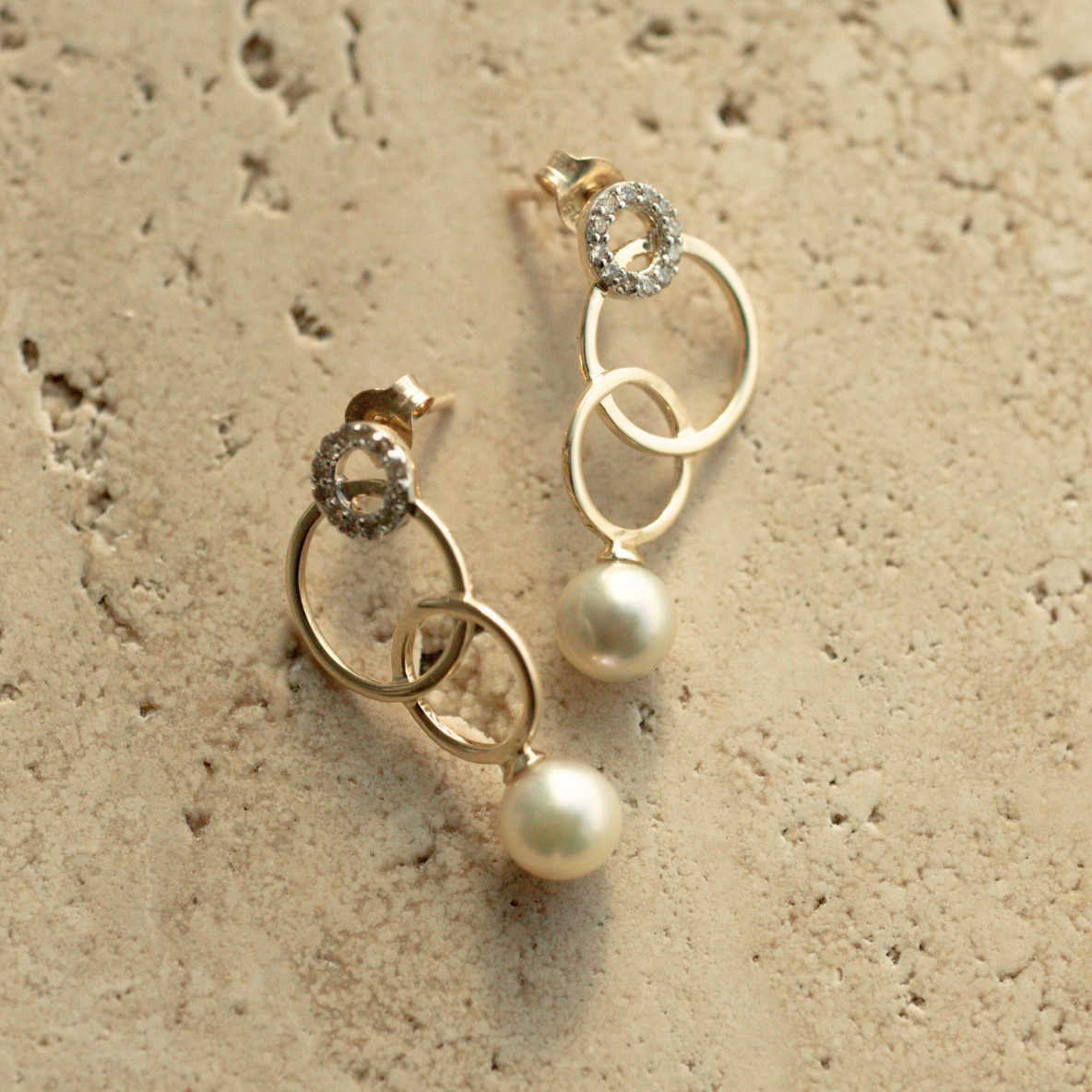 A pair of stunning pearl earrings featuring rings of gold in varying sizes.