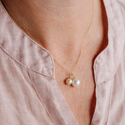 A woman wears her stunning Australian Pearl Charm set, featuring both an Akoya and South Sea pearl hung side by side on a gold chain.