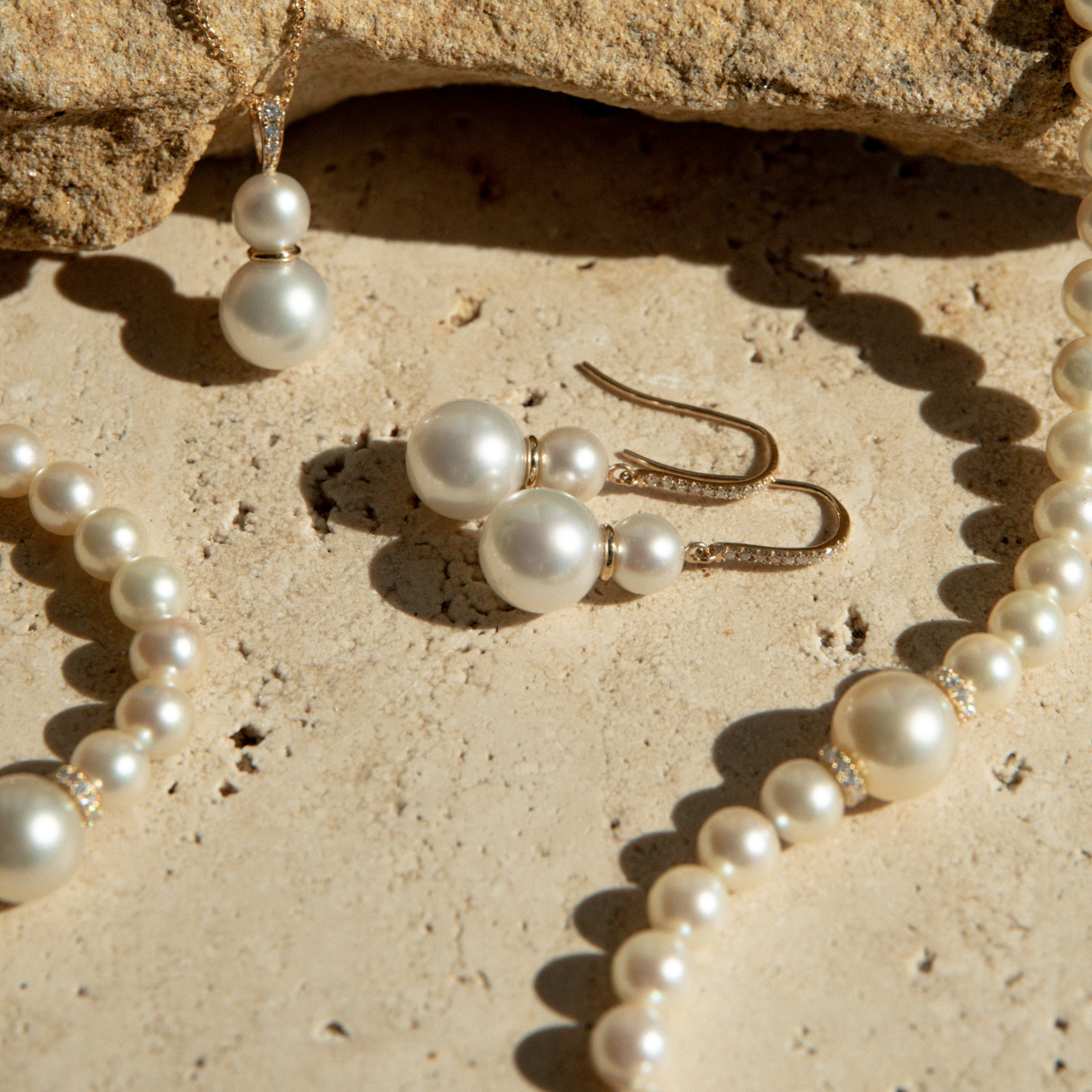 Pearl necklace and earrings on a sandy surface
