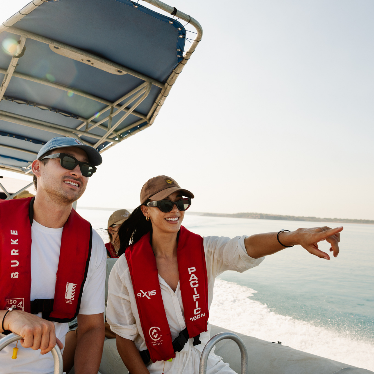 Two people on a boat wearing life vests with a scenic background at our Cygnet Bay Pearl Farm.