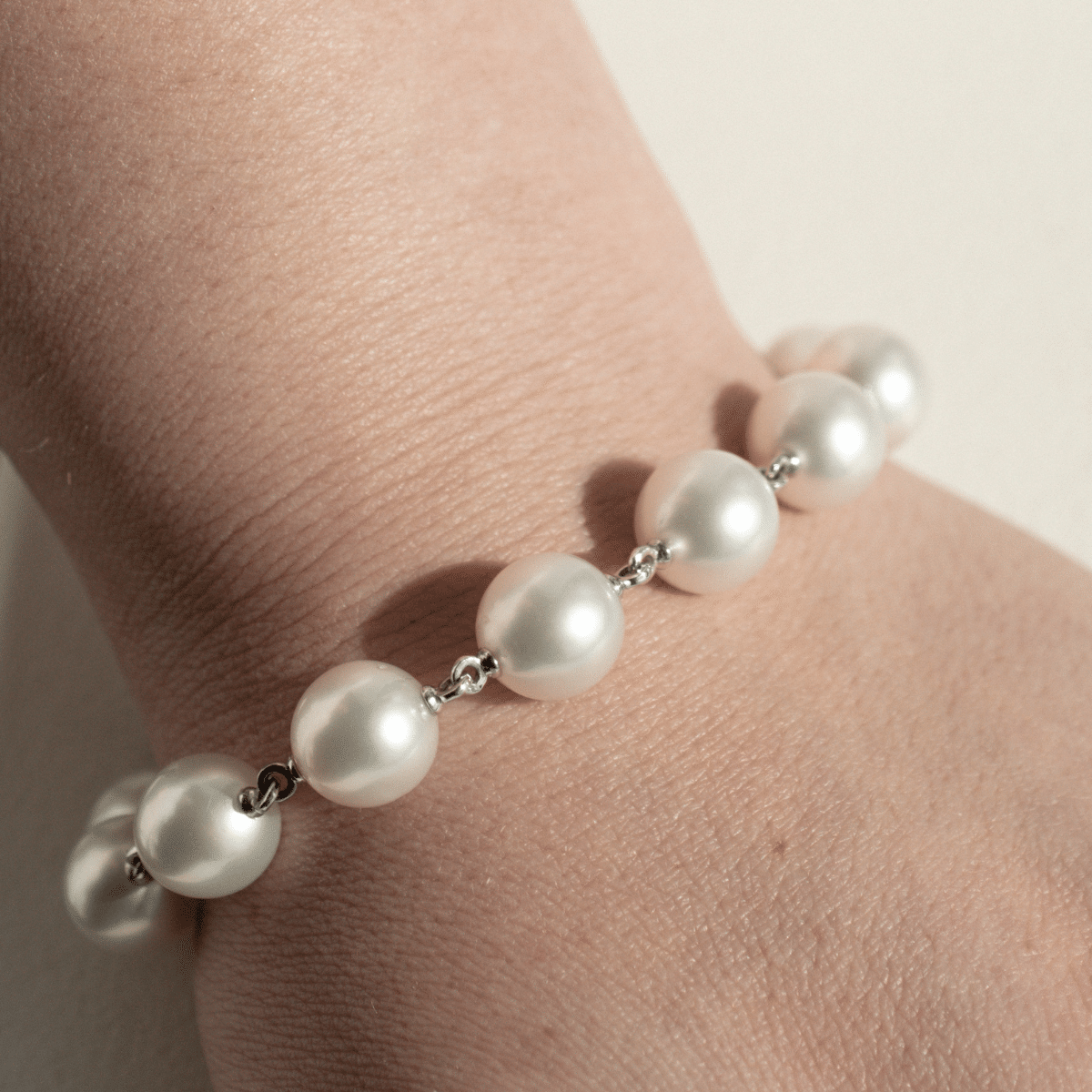 A woman wears her stunning Cocos Pearl Strand Bracelet, with pearls shining with their natural white colour and lustre. 