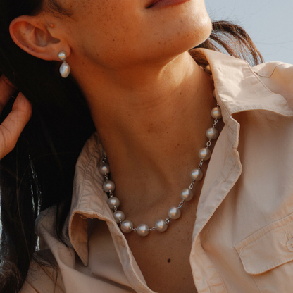 Close-up of a person wearing a pearl necklace and earrings.