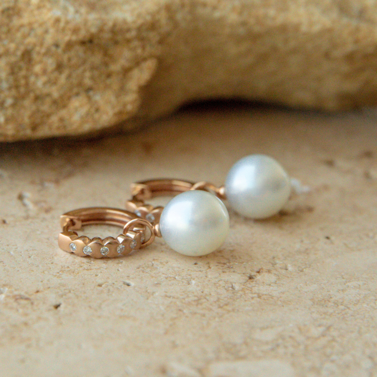 Pearl earrings on a sandy surface