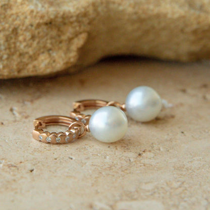 Pearl earrings on a sandy surface