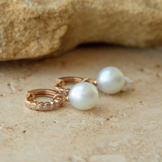 Pearl earrings on a sandy surface