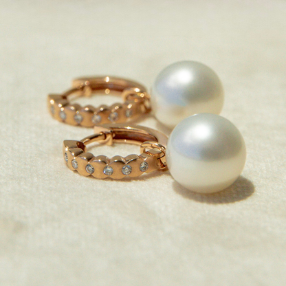 Gold hoop earrings with pearls on a light beige background