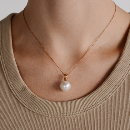 A woman wears her beautiful Australian South Sea pearl pendant set in gold with a single white diamond.