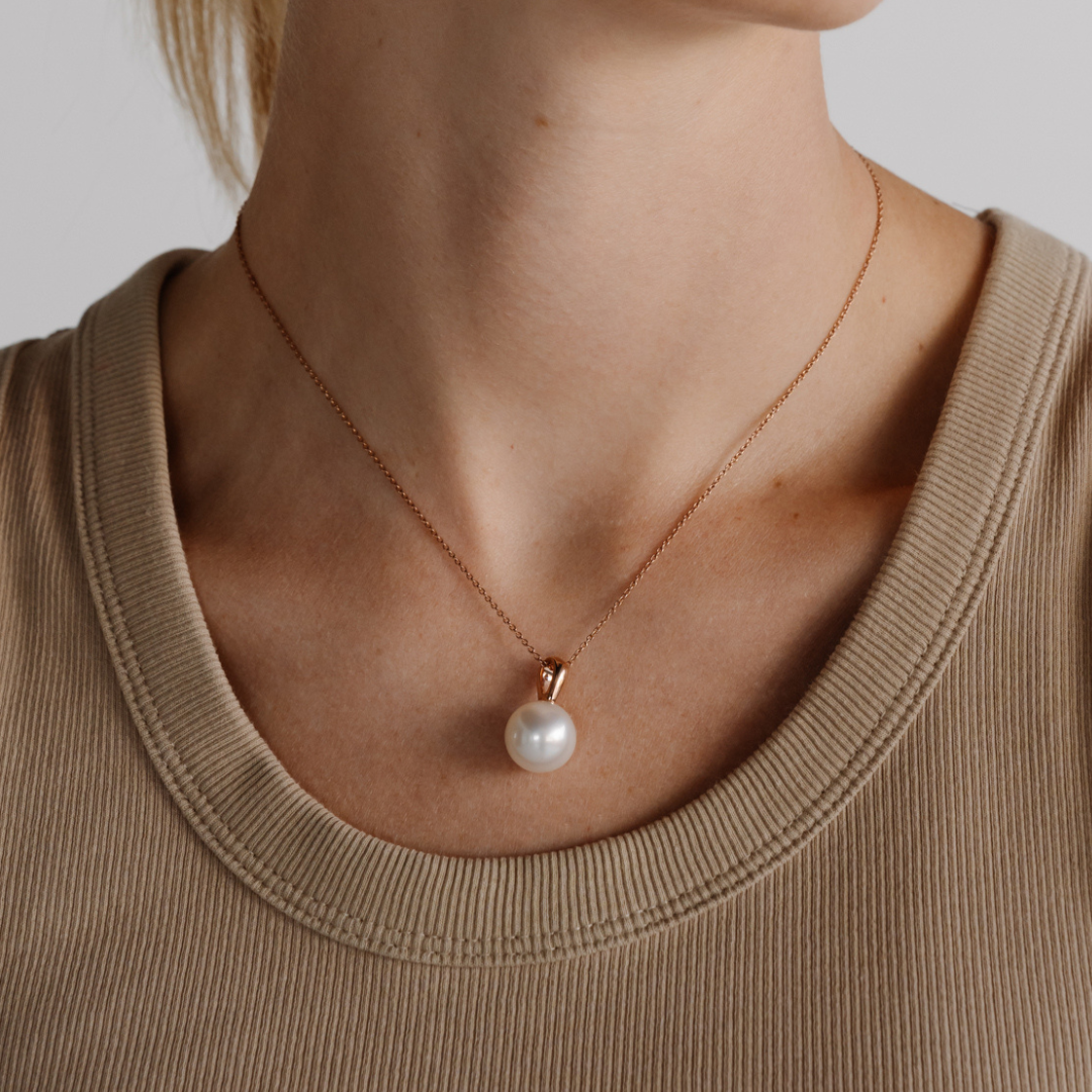 A woman wears her stunning Cocos Pearl Pendant featuring a drop shape Australian South Sea pearl set in gold.