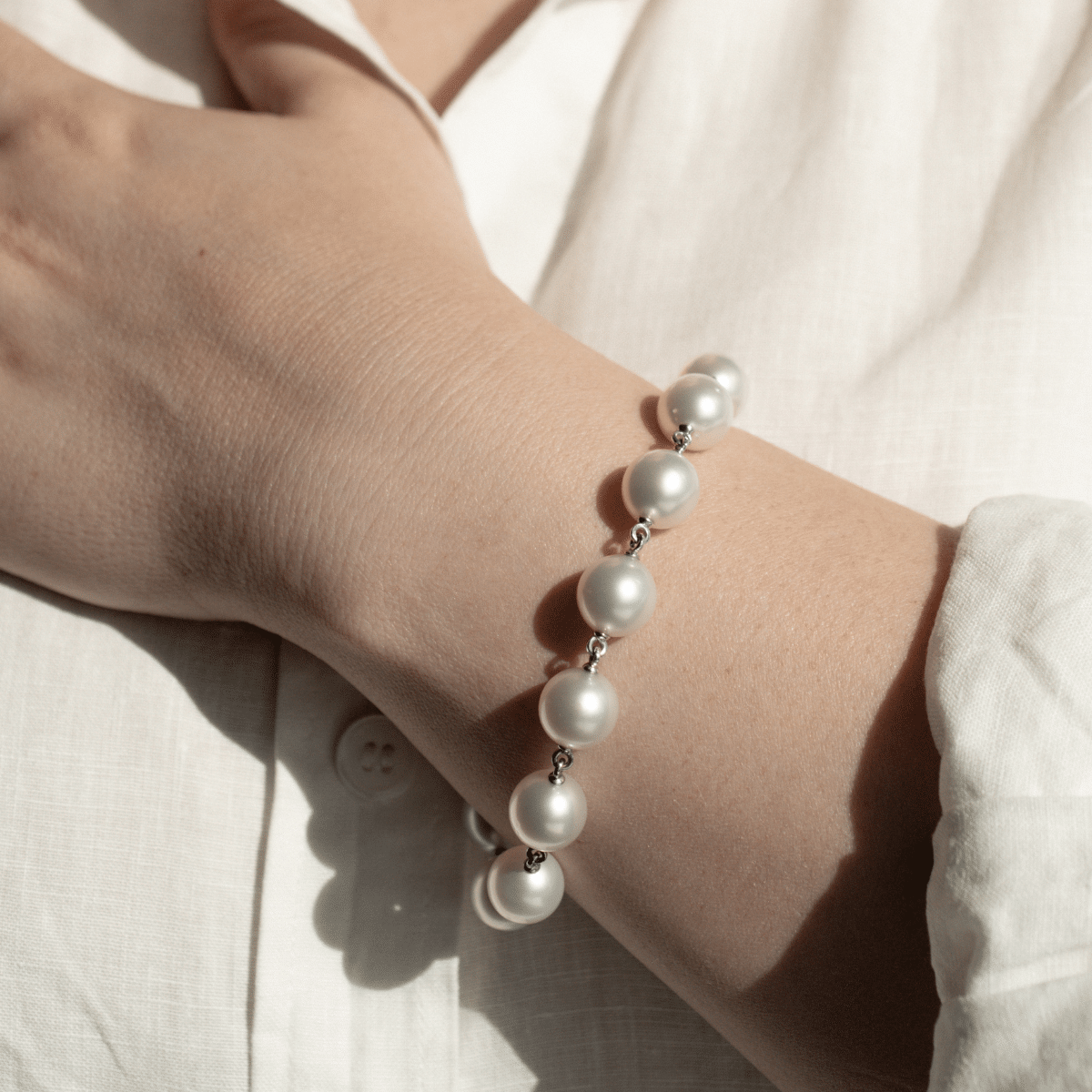 A woman wears her stunning Cocos Pearl Strand Bracelet, with pearls shining with their natural white colour and lustre. 