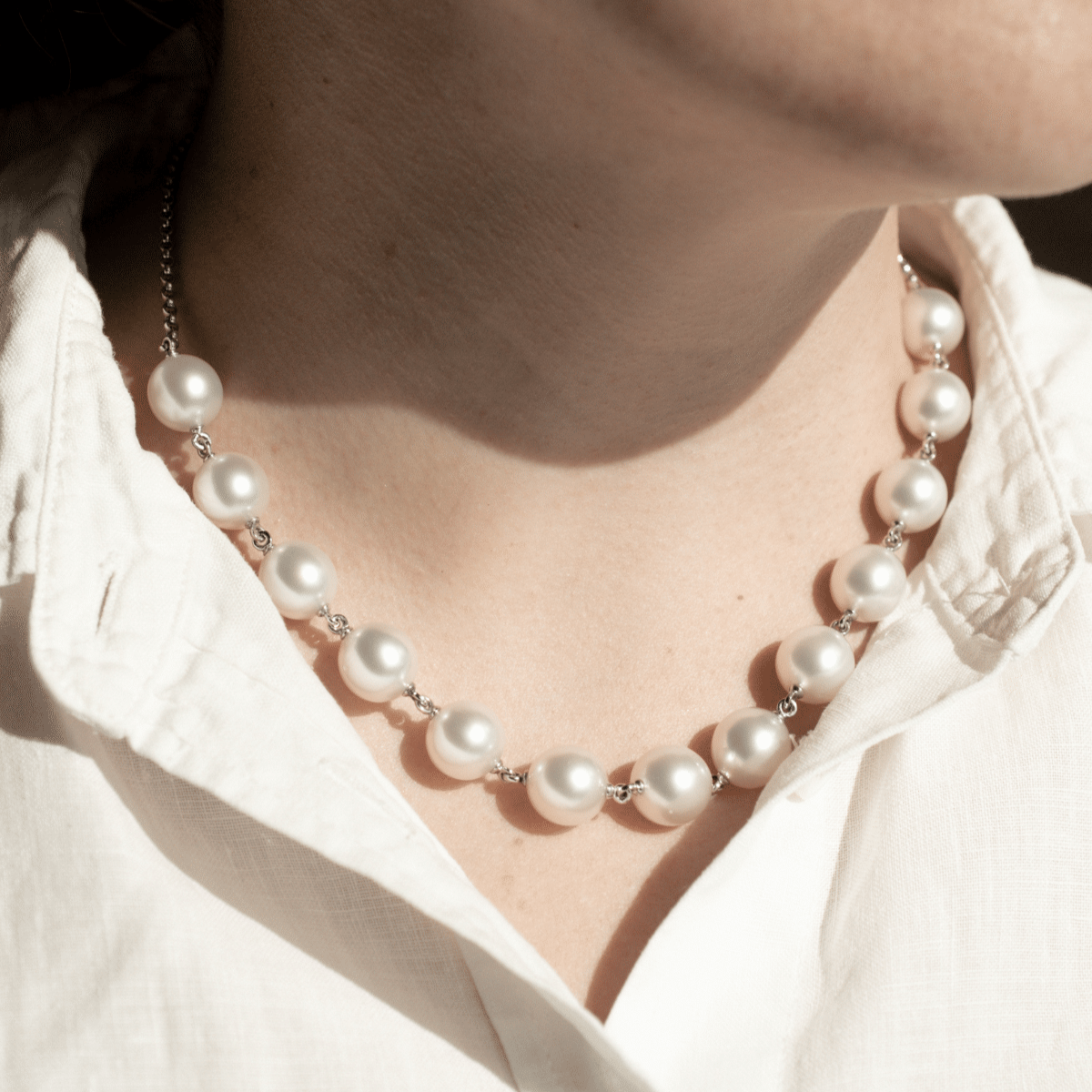 A woman wears her Cocos Pearl Strand Necklace features thirteen (13) drop shape Australian South Sea pearls set on a 43cm white gold chain.