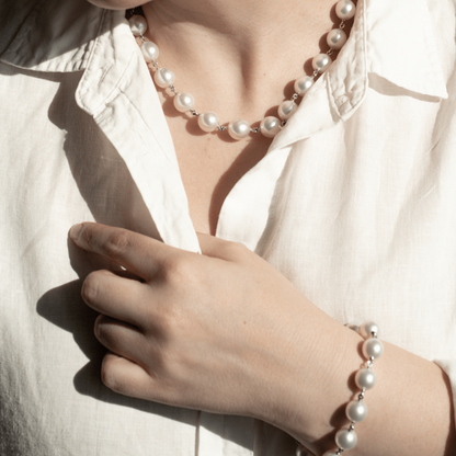 A woman wears her Cocos Pearl Strand Necklace featuring thirteen (13) drop shape Australian South Sea pearls set on a 43cm white gold chain. She wears her matching pearl strand bracelet to complete her set. 