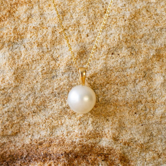 A stunning Cocos Pendant featuring a round Australian South Sea pearl set in gold, and hung from a matching gold chain. 