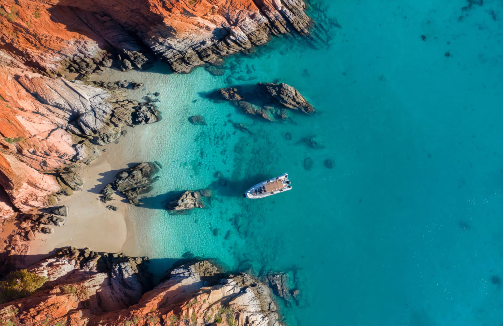 A boat sits on the still turquoise waters at Cygnet Bay Pearl Farm, surrounded by the beautiful pindan rock. 