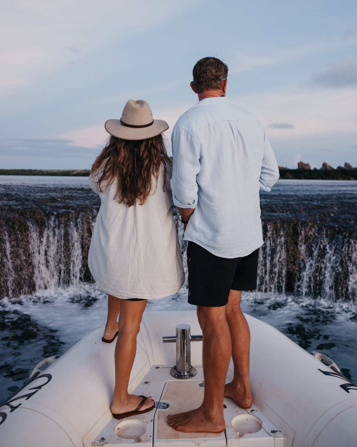 A couple stand at the end of a boat during a Waterfall Reef Sea Safari at our Cygnet Bay Pearl Farm. 