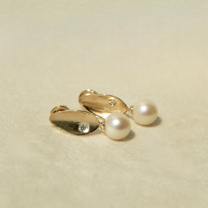 Pair of gold earrings with pearls on a beige background