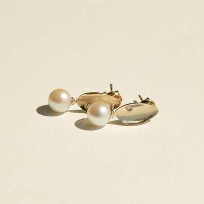 Gold earrings with pearls on a beige background