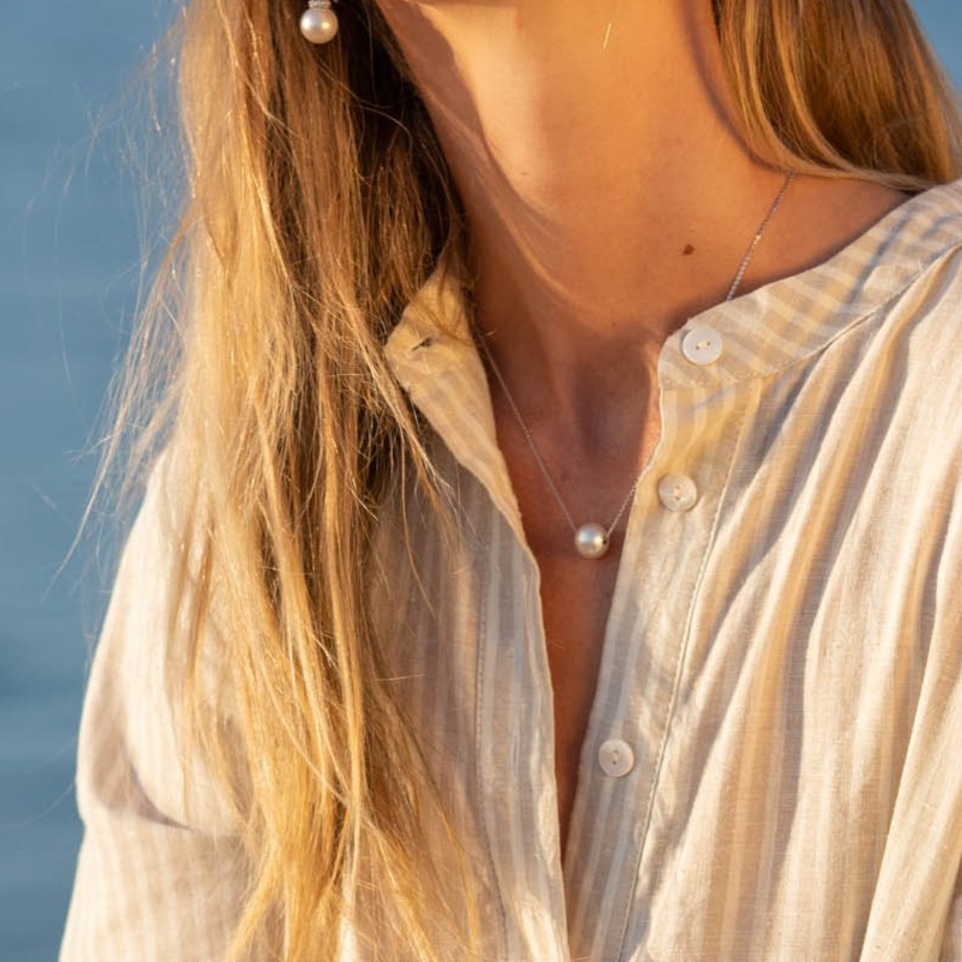 A woman wears her stunning Australian South Sea pearl set on a gold chain necklace.