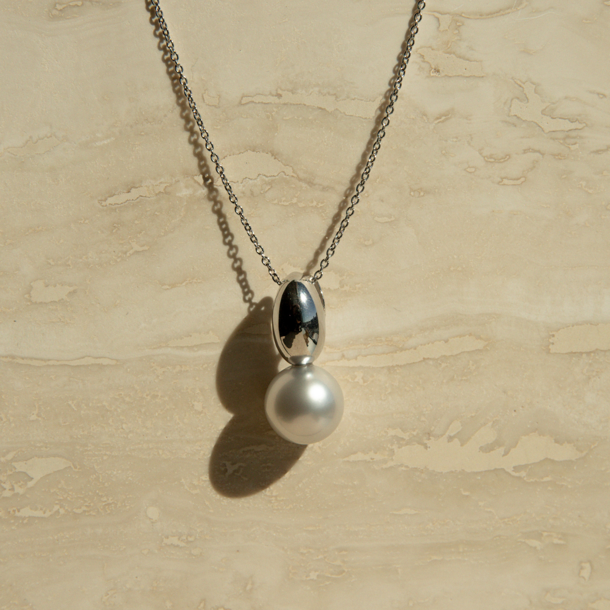 Necklace with a pearl pendant on a beige textured background