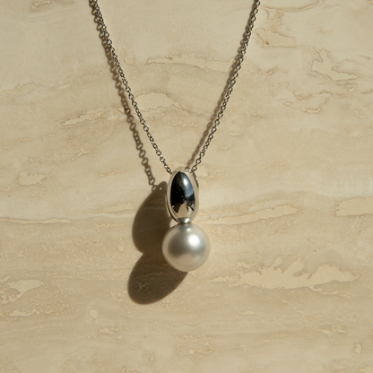Necklace with a pearl pendant on a beige textured background