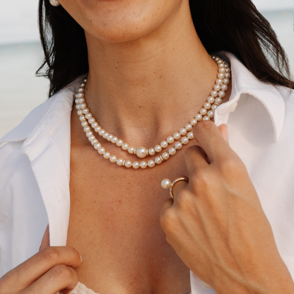 Person wearing a pearl necklace with a blurred background