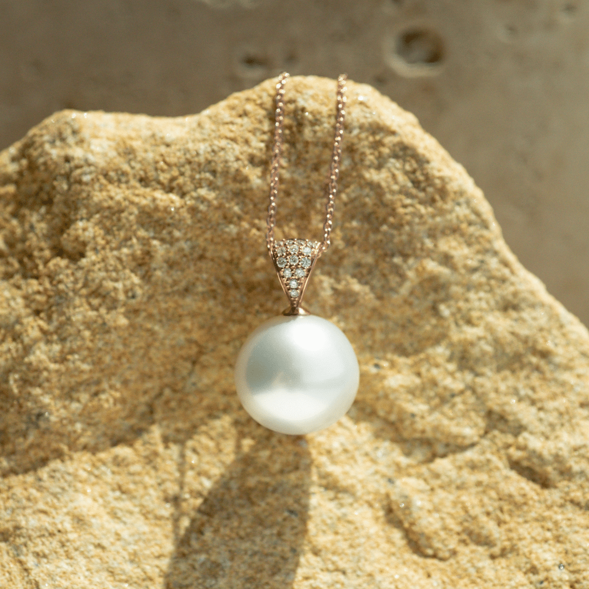 A stunning, round Australian South Sea pearl set in gold with 14 white diamonds glimmering alongside this classic design.