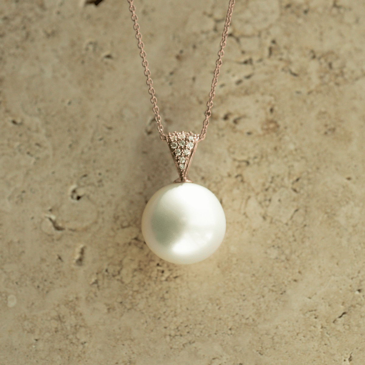 A stunning, round Australian South Sea pearl set in gold with 14 white diamonds glimmering alongside this classic design.