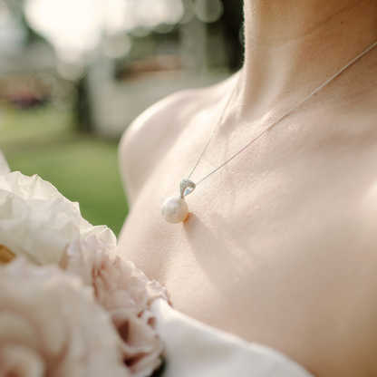 A bride wears her magnificent Eternal Grande Pearl Pendant, featuring an Australian South Sea pearl set alongside a myriad of glimmering white diamonds in gold.