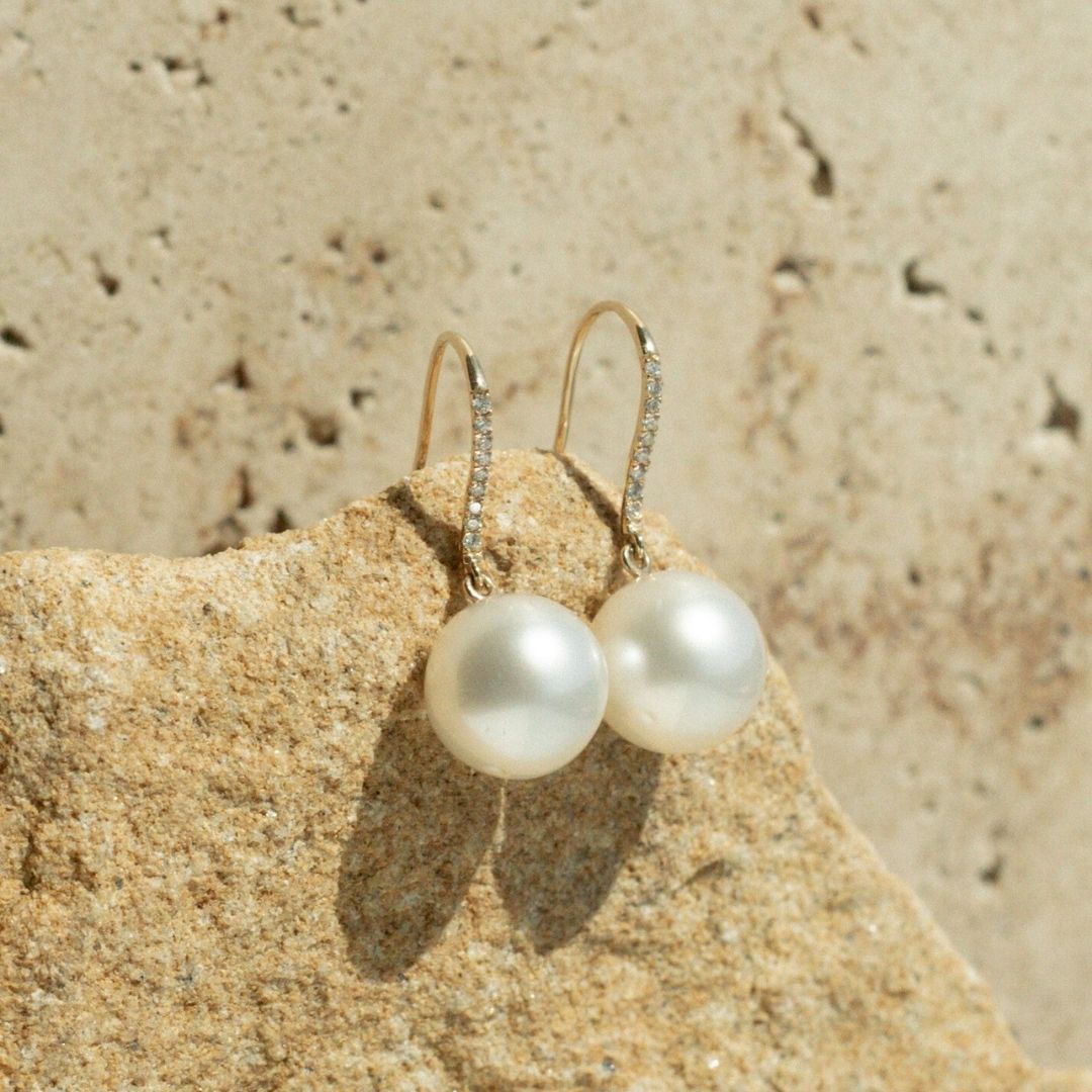 A pair of beautiful Australian South Sea pearls set on pearl hook earrings in gold, with a row of white glimmering diamonds as a feature of the design. 