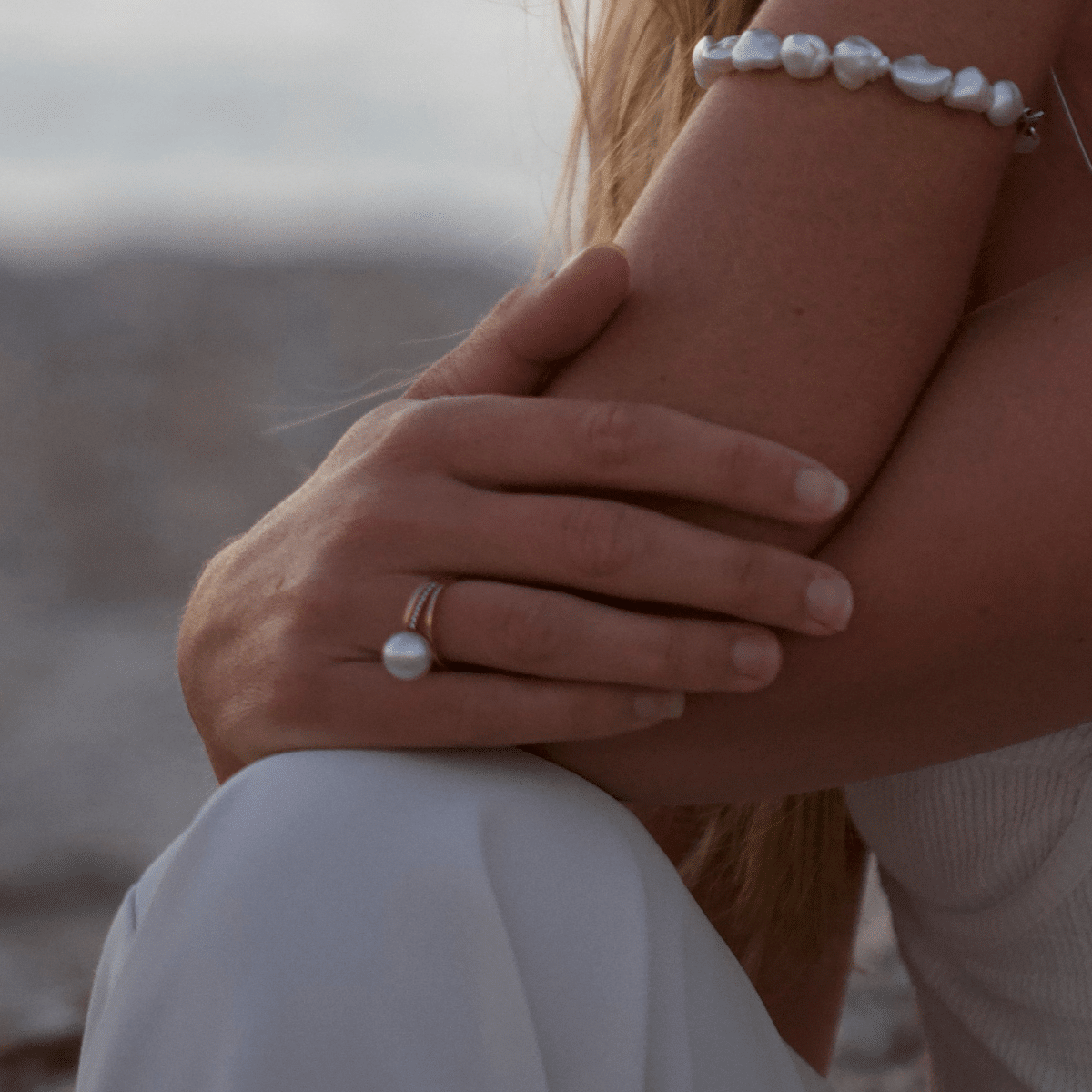 A woman wears her striking pearl ring, featuring an Australian South Sea pearl set alongside a band of white glimmering diamonds. 