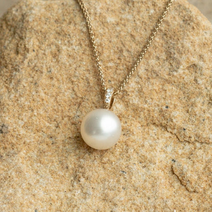 A beautiful Australian South Sea pearl set on a solid gold pendant featuring a row of white glimmering diamonds.