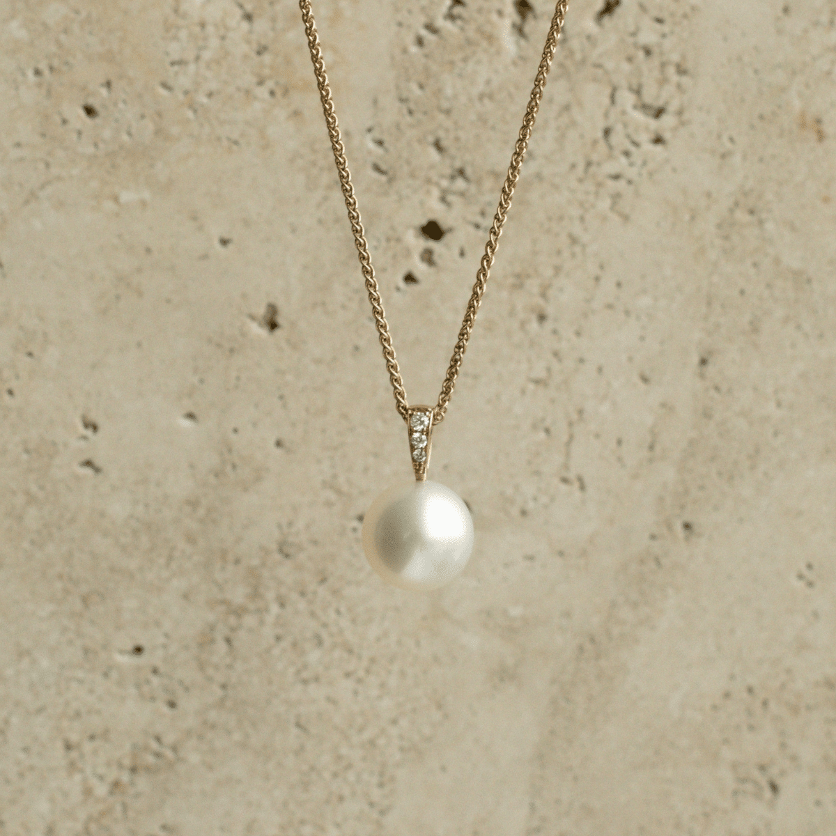 A beautiful Australian South Sea pearl set on a solid gold pendant featuring a row of white glimmering diamonds.