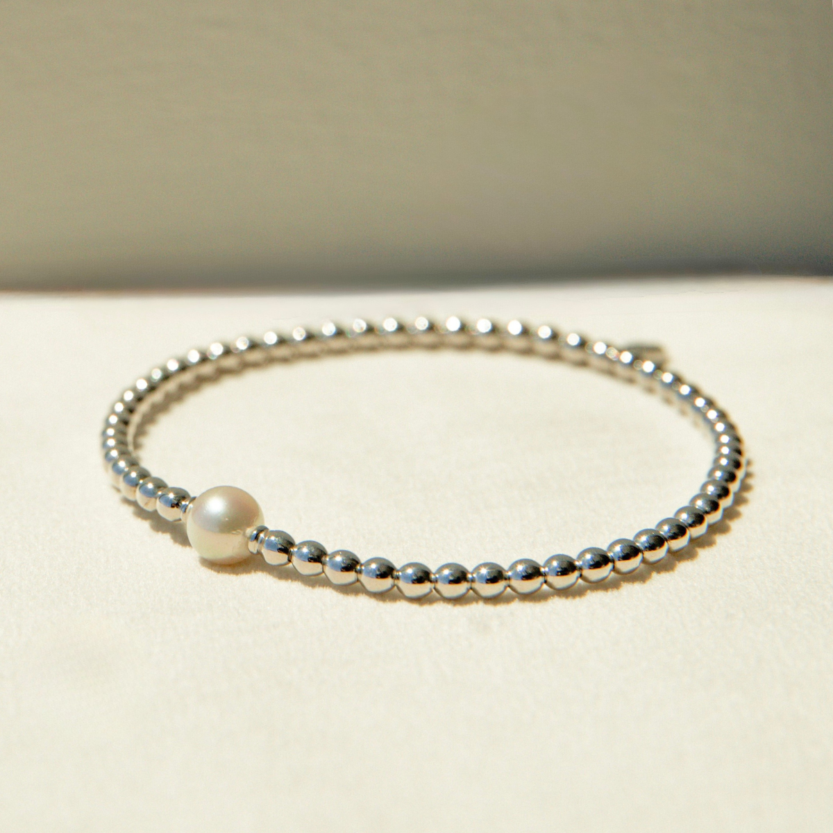 Pearl bracelet with silver beads on a beige background