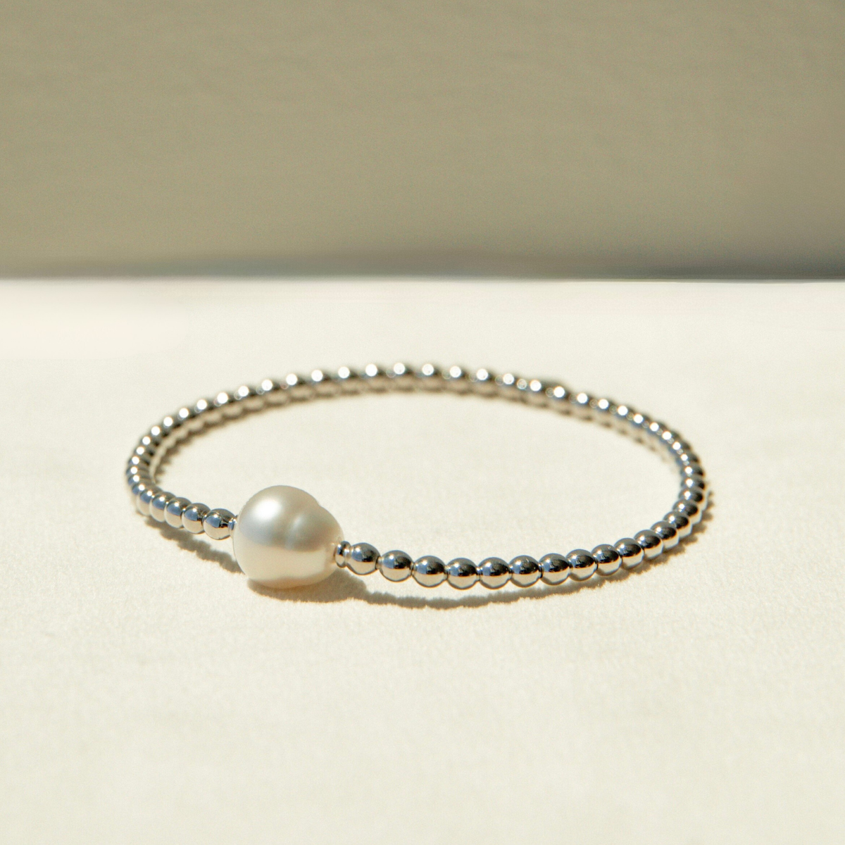 Pearl bracelet with silver beads on a beige background