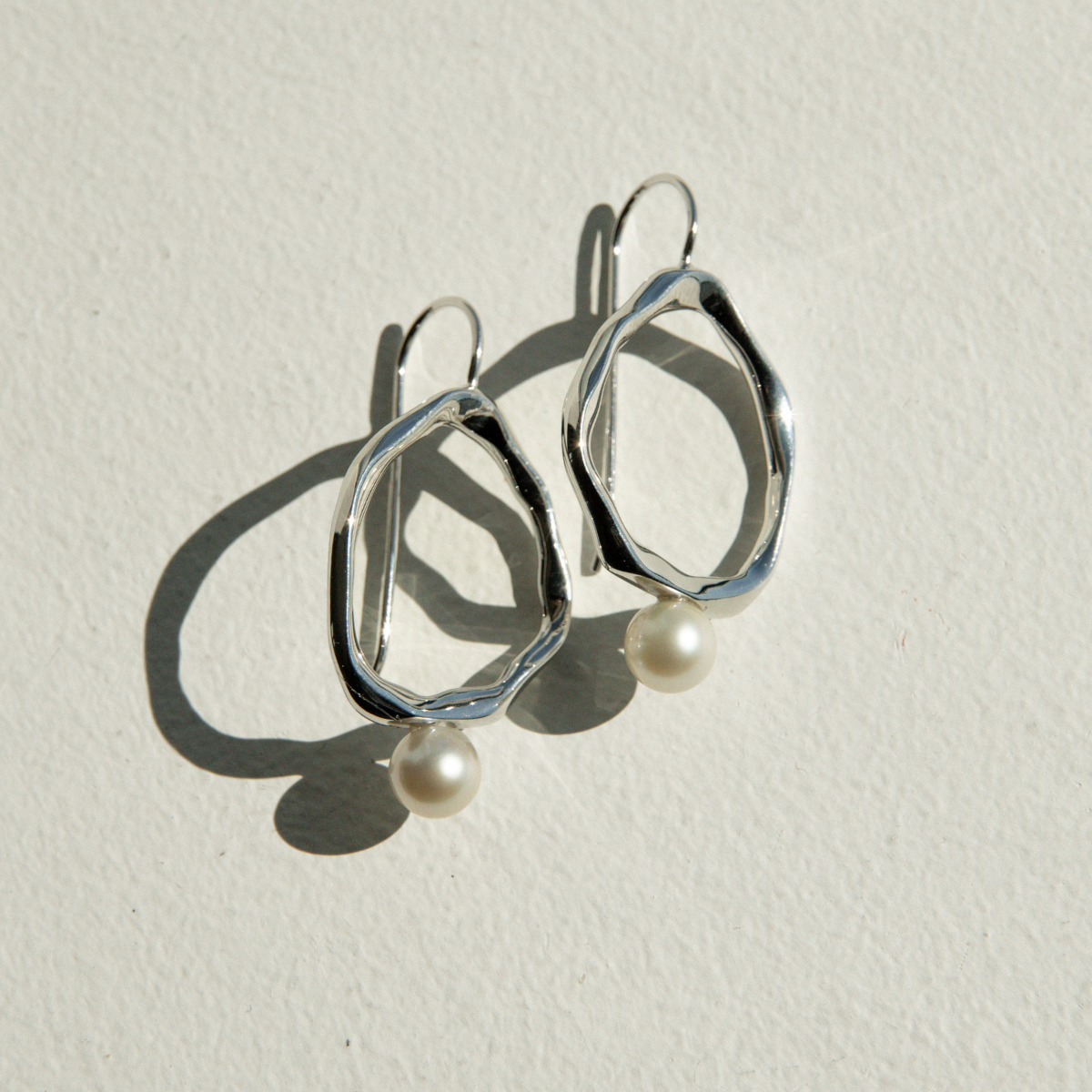 Silver earrings with pearl drops on a light background