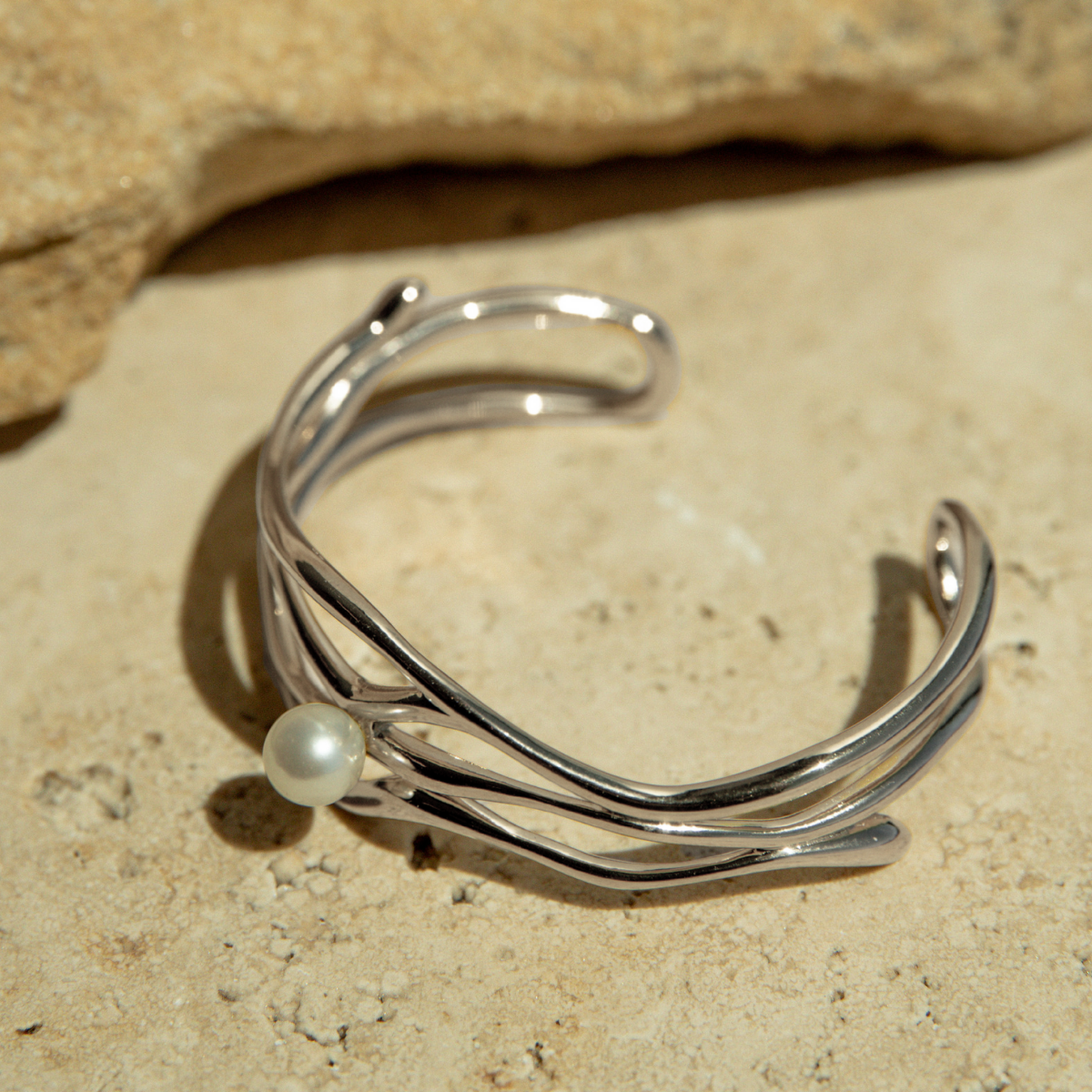 Silver bracelet with a pearl on a stone surface