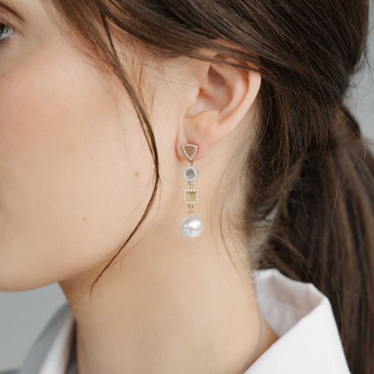 Close-up of a woman wearing a pearl earring with a gray background