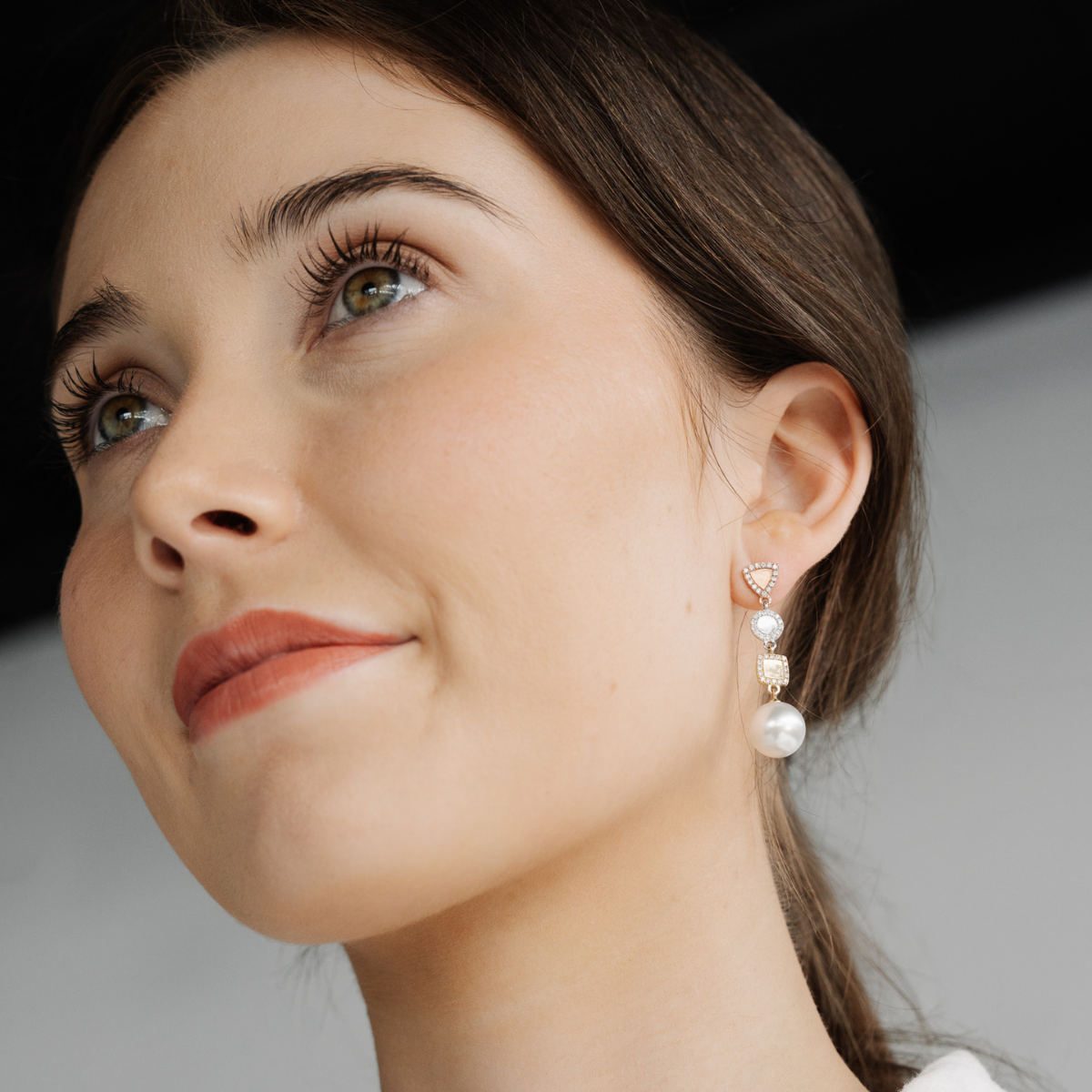Close-up of a woman wearing pearl earrings with a neutral background